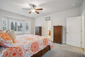 Bedroom featuring light colored carpet, a ceiling fan, and ensuite bath