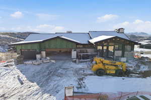 Snow covered structure featuring a mountain view and a garage