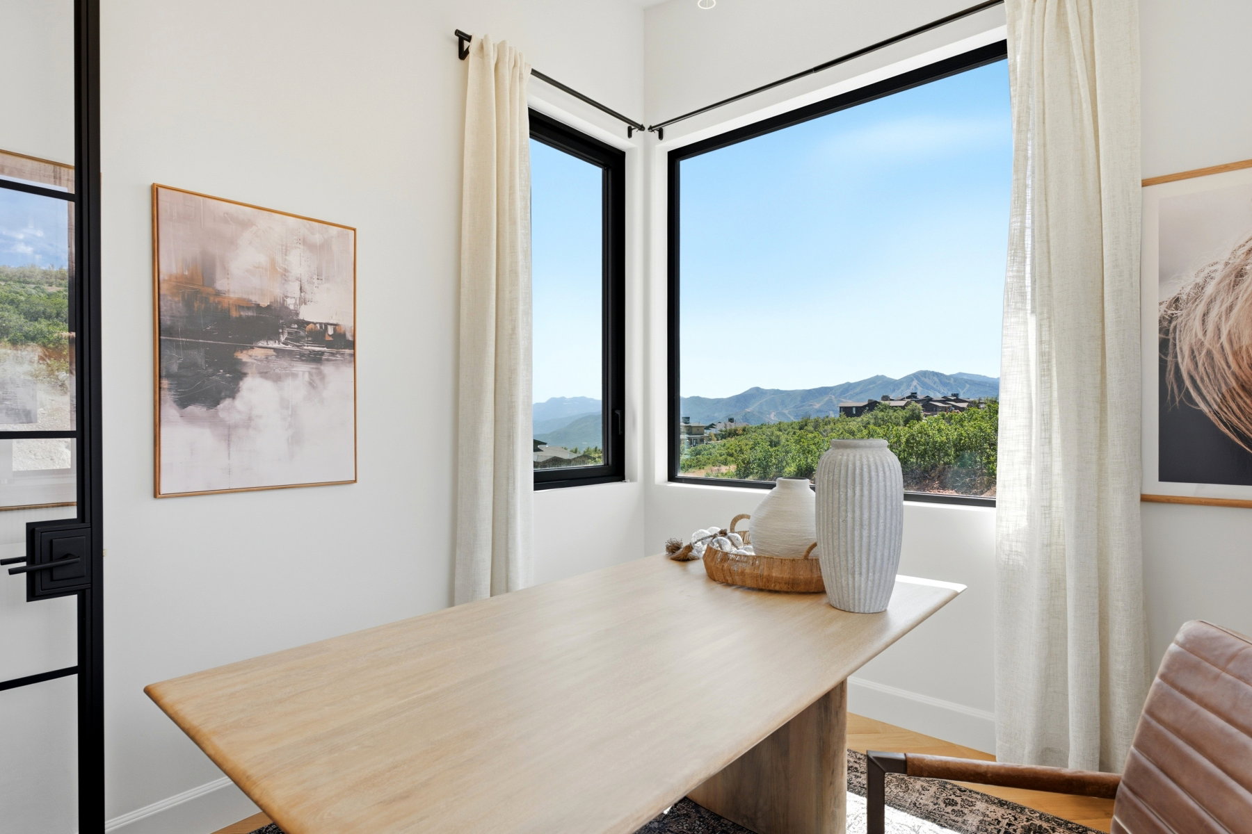 Corner window framing a mountainous landscape with a bright blue sky