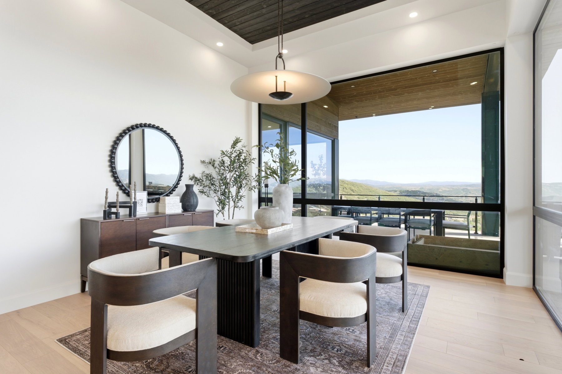 Dining area with expansive window wall, light wood-finish flooring, recessed lighting, and a dark wood ceiling detail