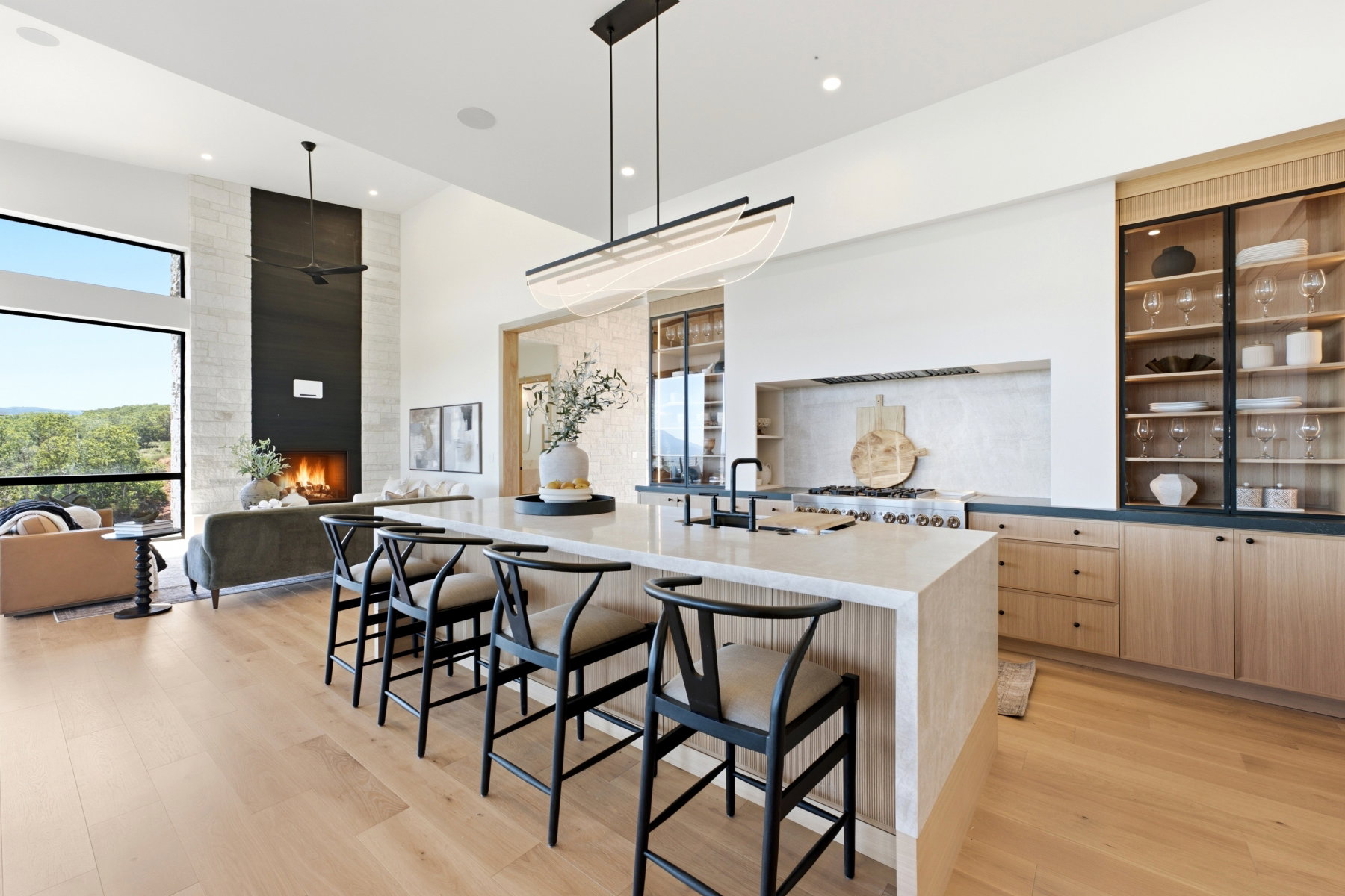 Open-concept kitchen featuring an expansive island with seating, a professional-grade range, and built-in display cabinetry