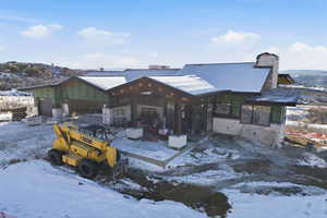 Snow covered back of property with a chimney and a metal roof