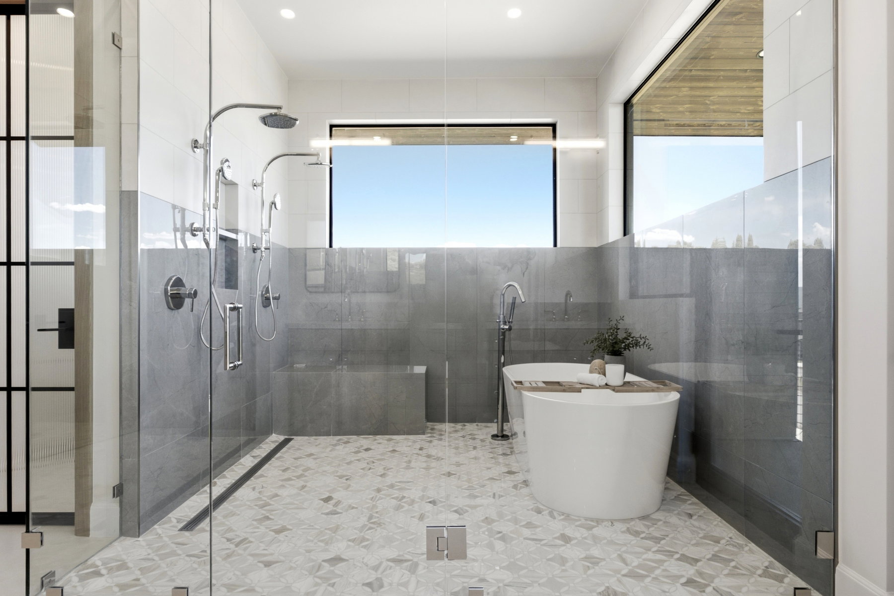 Spa-inspired bathroom featuring a freestanding soaking tub, a spacious glass-enclosed shower with multiple showerheads, geometric patterned floor tiling, large format wall tiling, and ample natural light from high windows