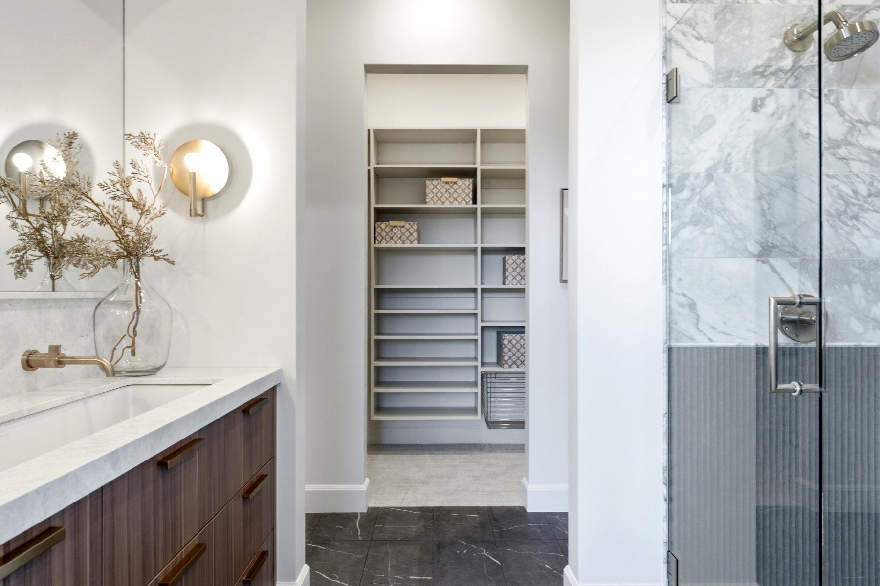 Bathroom featuring a wood-finish vanity with an integrated sink and wall-mounted faucet, complemented by a glass-enclosed shower with full-height marble-look tile