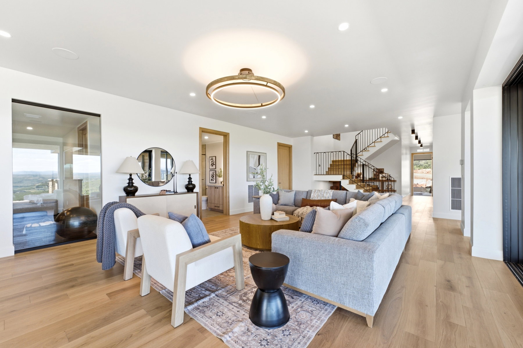 Open-concept living space featuring wood-finish flooring, recessed lighting, and a contemporary circular chandelier