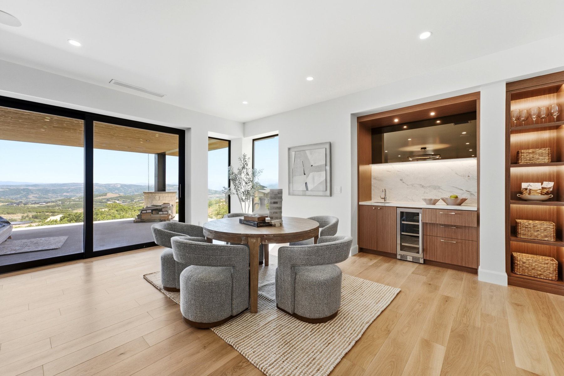Spacious room featuring wood-finish flooring, a built-in wet bar with a beverage refrigerator and marble backsplash, and integrated shelving with accent lighting