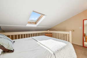 Bedroom with a skylight, carpet floors, and lofted ceiling