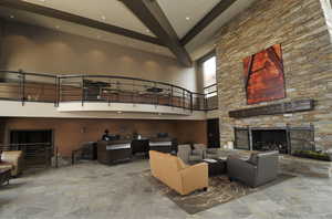 Living area featuring a high ceiling, recessed lighting, a fireplace, beamed ceiling, and stone floors