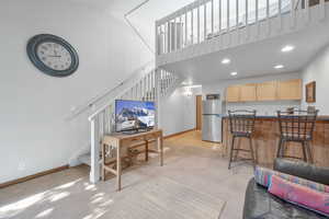 Living area featuring stairway, light colored carpet, recessed lighting, and a high ceiling