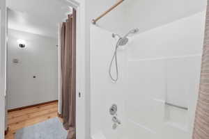 Bathroom with shower / bath combination with curtain and light wood-style flooring