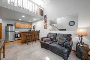 Living area featuring a towering ceiling, light colored carpet, recessed lighting, and stairway