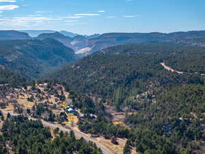 Aerial view of property's location with a mountain backdrop and a heavily wooded area