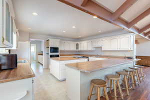 Kitchen with glass insert cabinets, a peninsula, light countertops, white cabinetry, and recessed lighting