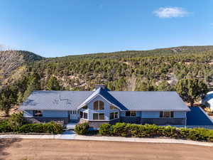 View of front of home featuring a forest view, a metal roof, and a chimney