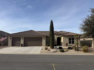 Mediterranean / spanish home with stucco siding, an attached garage, concrete driveway, and a tiled roof