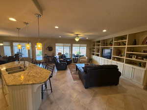 Living room featuring custom built in shelves, recessed lighting, ceiling fan, and light tile patterned flooring