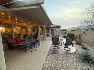 Patio terrace at dusk featuring outdoor dining space, a patio, a fenced backyard, and an outdoor hangout area