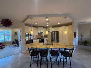 Kitchen with appliances with stainless steel finishes, double ovens, a kitchen bar, decorative light fixtures, backsplash, and light granite counters