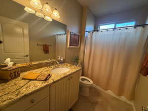 Bathroom featuring granite covered vanity, shower / tub combo, and dark tile patterned floors