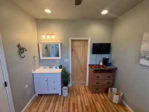 Sink in Casita with rest of bathroonm behind door.  Light wood-type flooring, recessed lighting, and ceiling fan