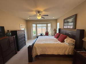 Primary Bedroom with light colored carpet, bay window, ceiling fan, and recessed lighting