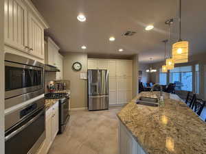 Kitchen with stainless steel appliances, a chandelier, recessed lighting, hanging light fixtures, and light granite counters