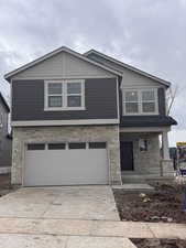 Craftsman-style home with stone siding, covered porch, concrete driveway, and an attached garage