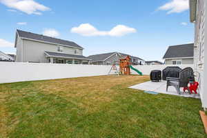Fenced backyard with a playground, a patio area, and a residential view
