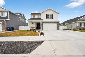 View of front facade with a gate, driveway, a garage, and brick siding