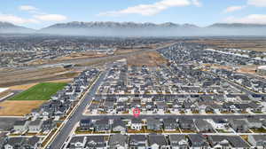 Aerial view of property and surrounding area featuring nearby suburban area and a mountainous background