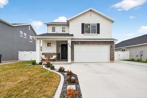 View of front of house with a gate, covered porch, stone siding, concrete driveway, and an attached garage