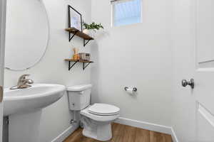 Half bathroom featuring toilet and wood finished floors