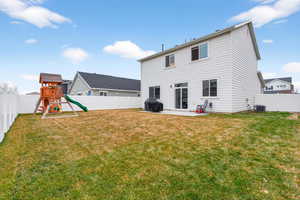 Rear view of house featuring a playground, a patio area, and a fenced backyard