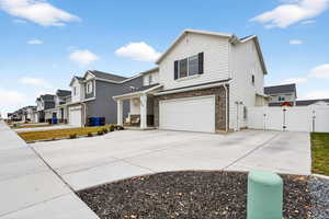 View of front facade with a gate, concrete driveway, stone siding, a garage, and a residential view