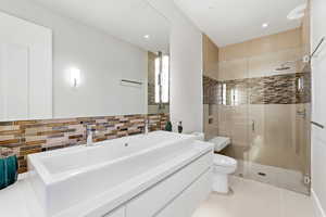 Bathroom with double vanity, a stall shower, decorative backsplash, and recessed lighting