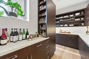 Bar featuring dark brown cabinets, open shelves, light wood-style floors, and modern cabinets
