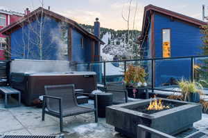 Patio terrace at dusk with a hot tub, an outdoor fire pit, and a patio