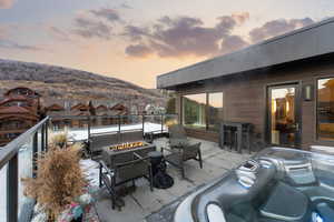 Patio terrace at dusk featuring a patio area, a hot tub, area for grilling, an outdoor living space with a fire pit, and a residential view