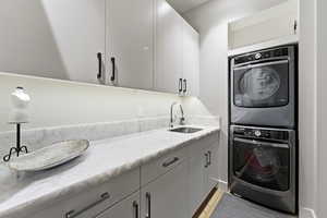 Laundry room featuring stacked washer / drying machine and cabinet space