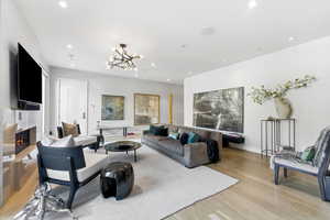 Living area featuring light wood-type flooring, a chandelier, a premium fireplace, and recessed lighting