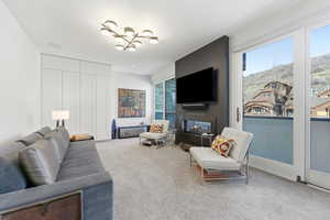 Living room with carpet flooring, a fireplace, and a chandelier