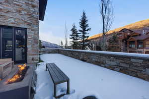 Snow covered back of property with a mountain view and an outdoor fire pit