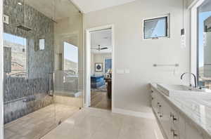 Ensuite bathroom with a tile shower, vanity, a ceiling fan, and healthy amount of natural light