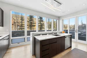 Kitchen featuring an island with sink, light stone countertops, plenty of natural light, light wood-type flooring, and recessed lighting