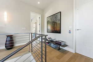 Hallway featuring an upstairs landing and light wood-style flooring