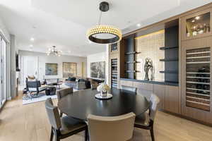 Dining space with built in features, recessed lighting, light wood-type flooring, and a chandelier