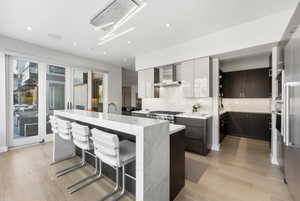 Kitchen featuring modern cabinets, light stone counters, light wood-type flooring, a kitchen island with sink, and recessed lighting