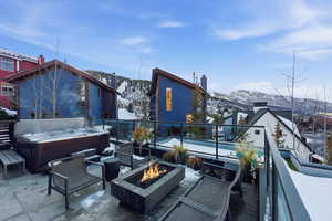 View of patio with a hot tub, a mountain view, and an outdoor living space with a fire pit