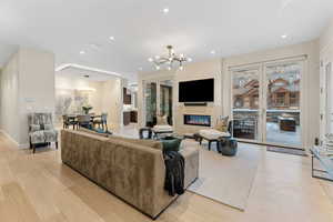 Living room featuring a glass covered fireplace, recessed lighting, light wood-type flooring, and a chandelier