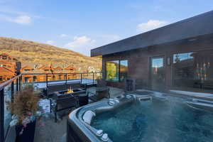 View of patio / terrace featuring a fire pit, a hot tub, and a mountain view